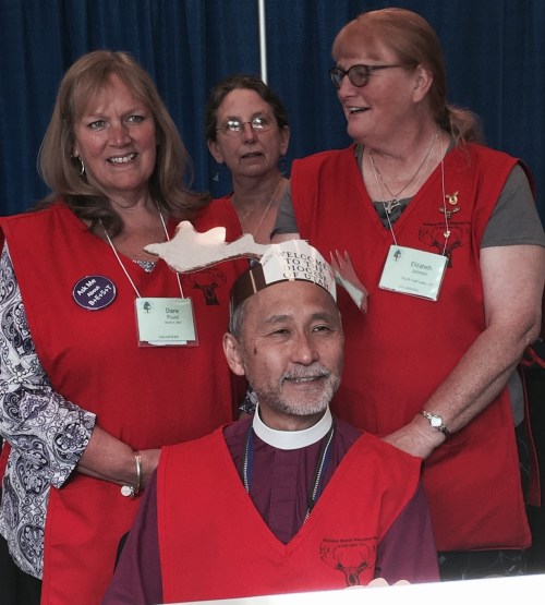 Diane Pound (upper left) helps Utah's Bishop Hayashi get suited up appropriately to serve as a General Convention volunteer for a day.